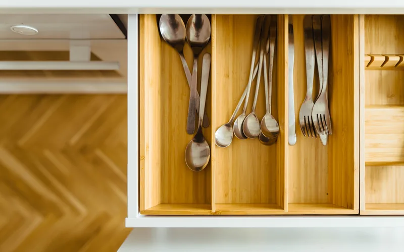 Offene Schublade mit Besteckeinsatz aus hellem Holz